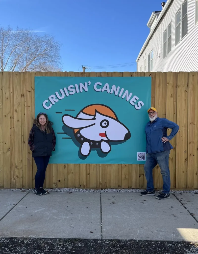 two people standing in front of a banner reading "Cruisin Canines"